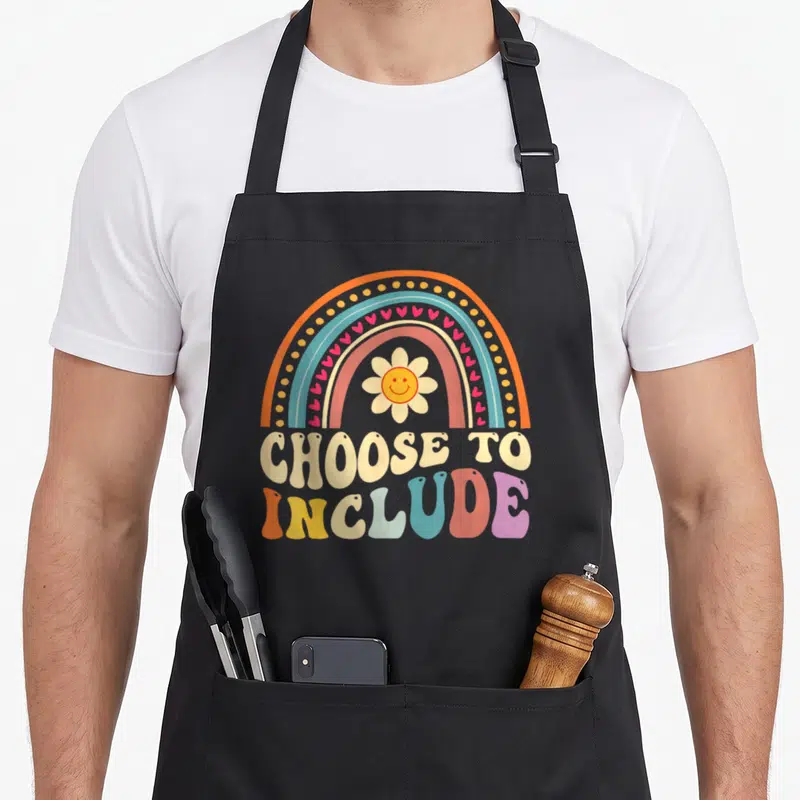 Choose teacher art apron - Retro rainbow with sunflower and CHOOSE TO INCLUDE text in orange, blue, yellow, pink, beige — shown on a black cotton canvas apron against a white background