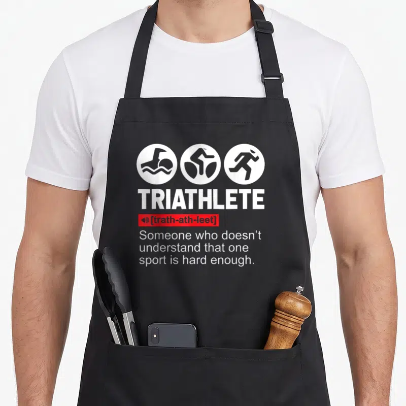 Sport triathlete apron - TRIATHLETE definition with swim bike run icons in white and red on black apron — shown on a black cotton canvas apron against a white background