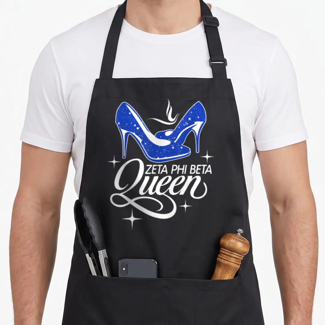 Sisterhood sorority apron - Two blue high heel shoes above Zeta Phi Beta Queen text with white sparkles — shown on a black cotton canvas apron against a white background