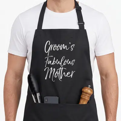 Fabulous bridal apron - White stacked script text Groom's Fabulous Mother on grey background — shown on a black cotton canvas apron against a white background
