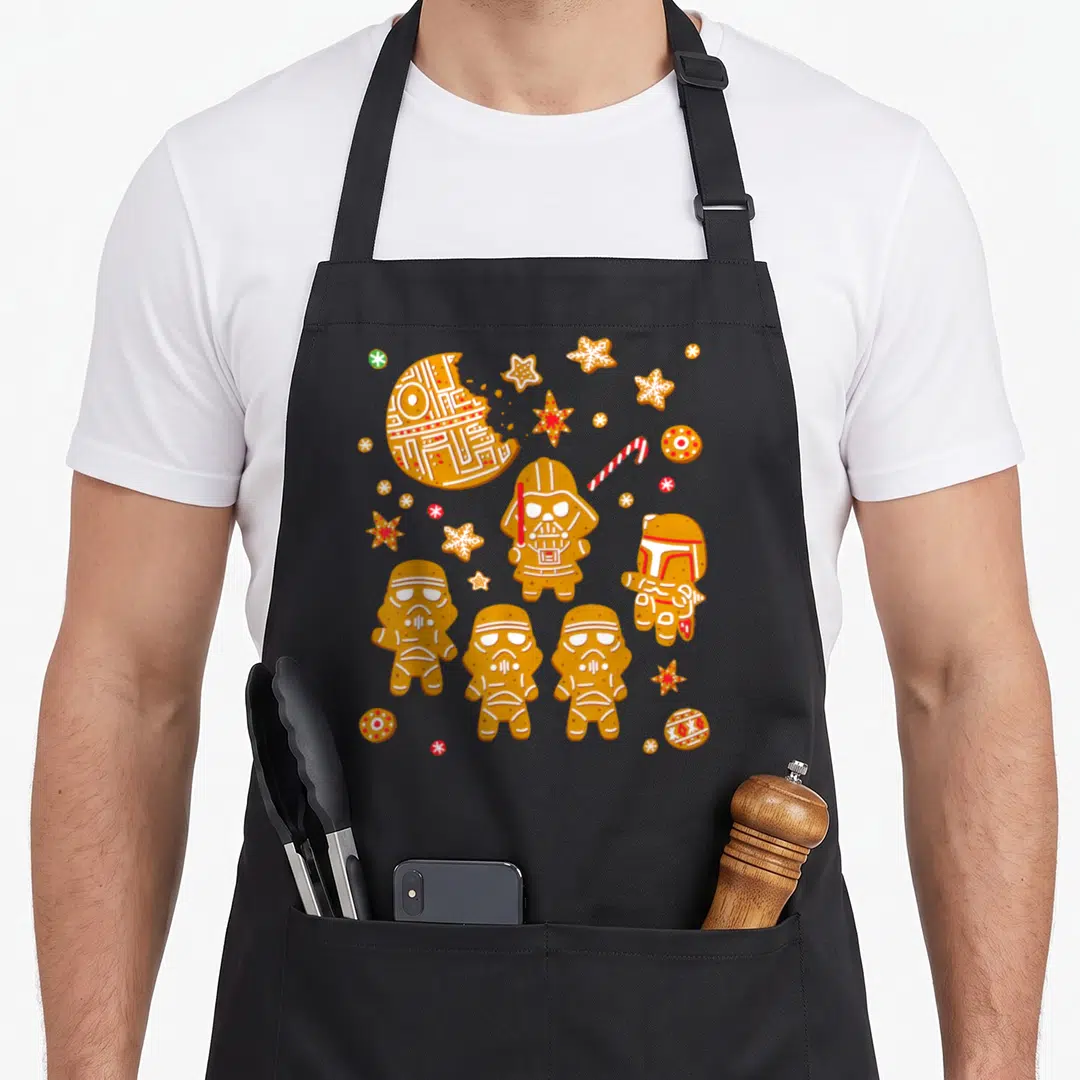 Gingerbread cookies apron - Star Wars characters as gingerbread cookies with white and red icing decorations — shown on a black cotton canvas apron against a white background