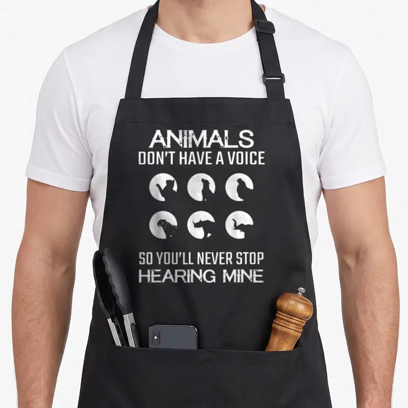 Voice animal apron - White distressed text and six circular animal silhouettes on black background — shown on a black cotton canvas apron against a white background