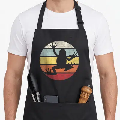 Frog tree apron - Grey frog silhouette over white blue yellow red striped circle — shown on a black cotton canvas apron against a white background