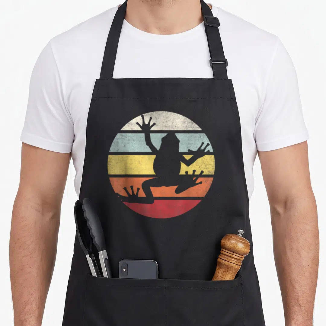Frog tree apron - Grey frog silhouette over white blue yellow red striped circle — shown on a black cotton canvas apron against a white background