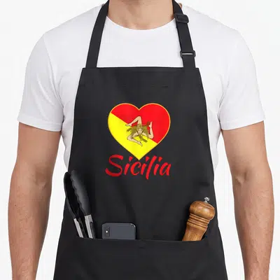 Pride sicily apron - Red and yellow heart with Trinacria symbol and red Sicilia text below — shown on a black cotton canvas apron against a white background