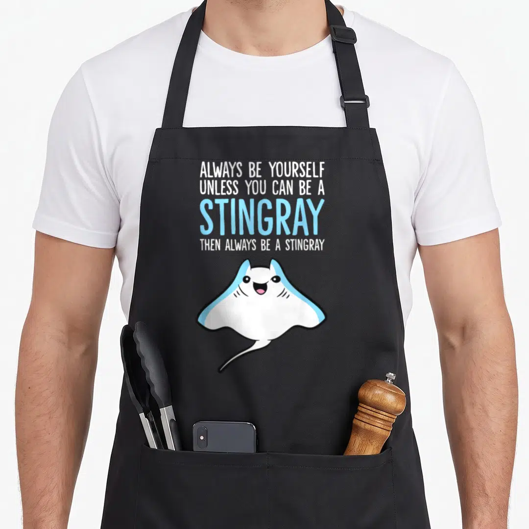Unless i love my penguin apron - Stacked white and blue text above a smiling cartoon stingray with black outline — shown on a black cotton canvas apron against a white background