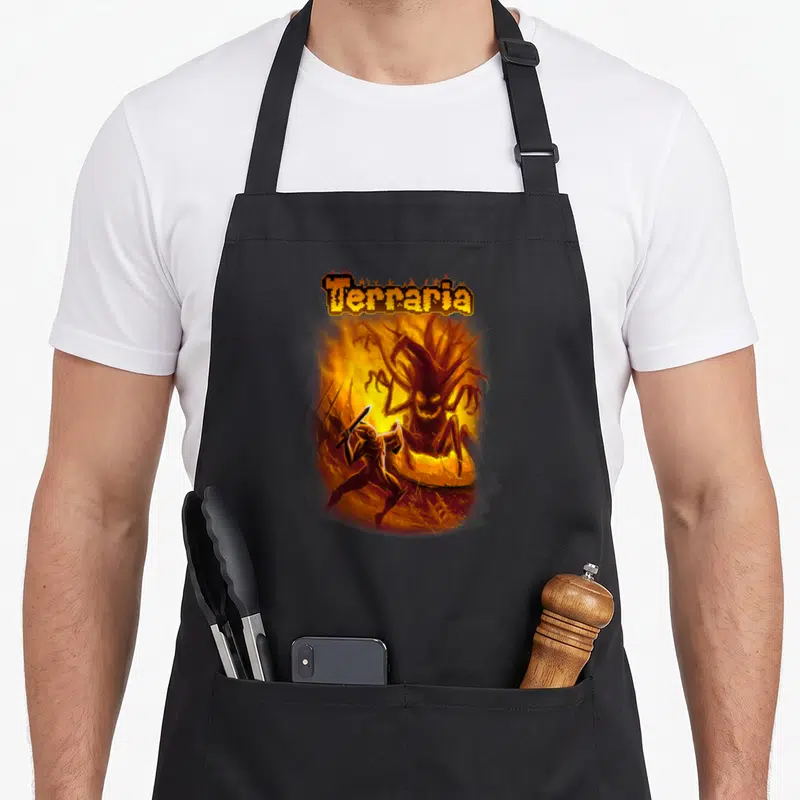 Terraria wood apron - Pixelated Terraria text above a warrior fighting a large flaming tree monster in orange and brown — shown on a black cotton canvas apron against a white background