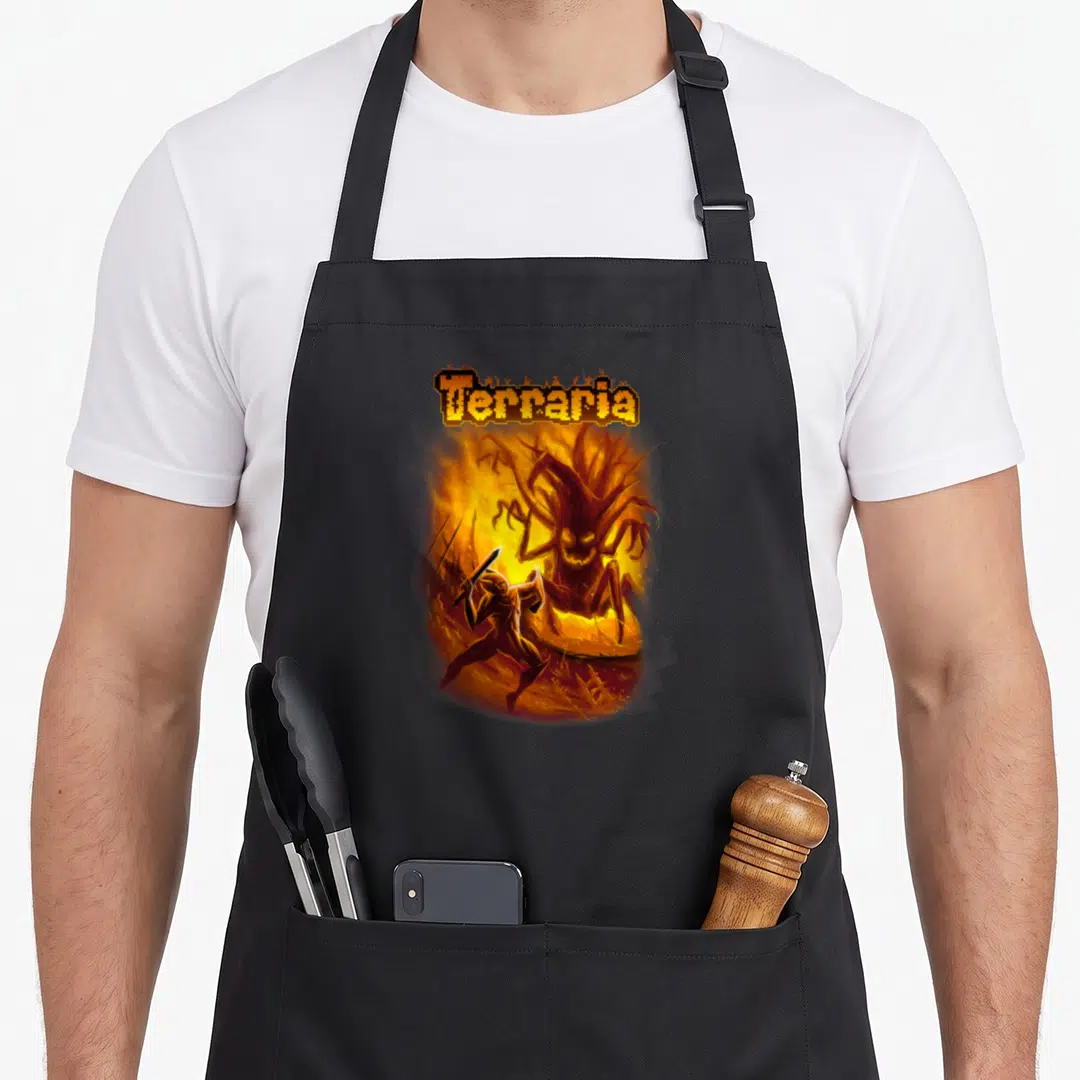 Terraria wood apron - Pixelated Terraria text above a warrior fighting a large flaming tree monster in orange and brown — shown on a black cotton canvas apron against a white background