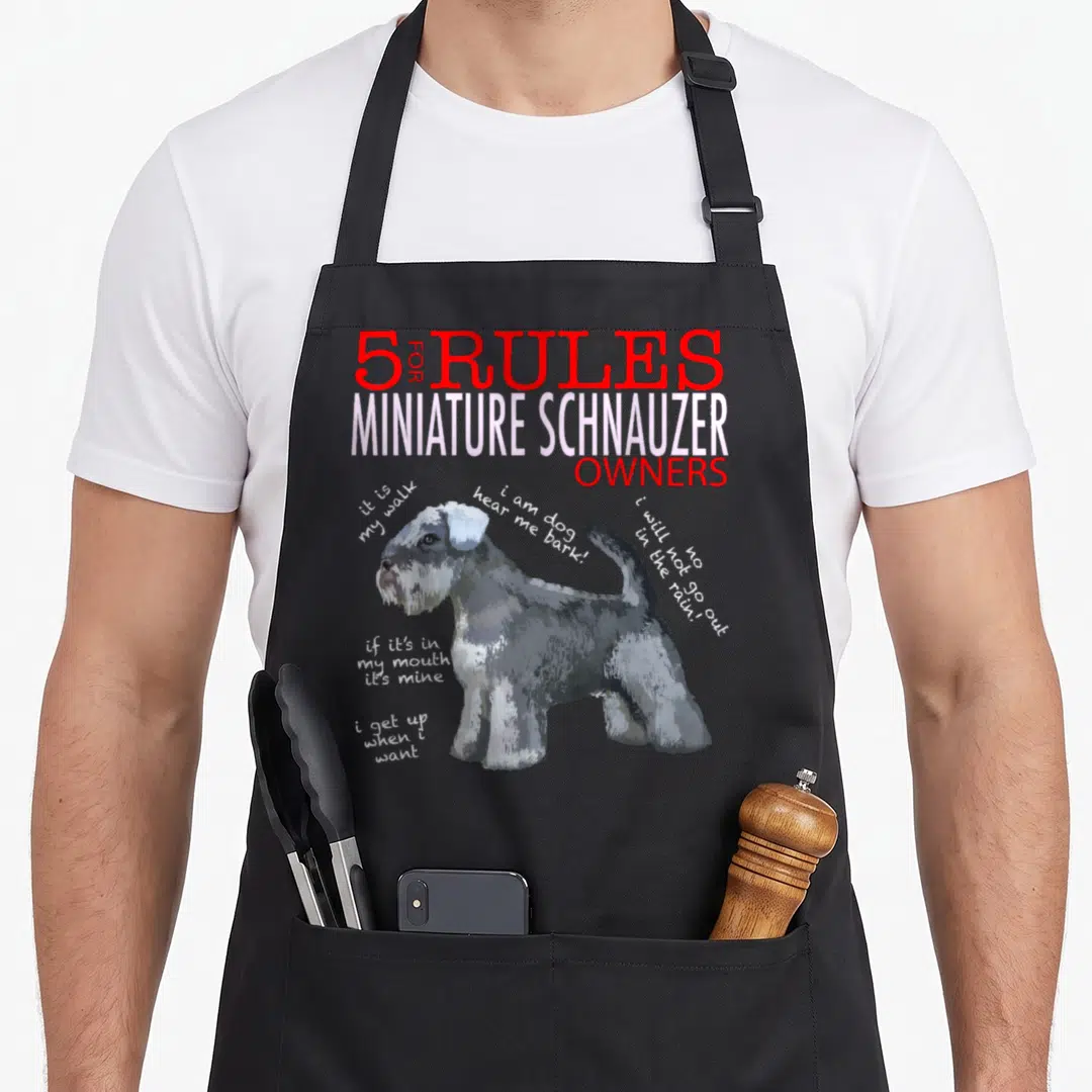 Rule miniature schnauzer apron - Cartoon miniature schnauzer with 5 rules text and handwritten quotes on grey background — shown on a black cotton canvas apron against a white background