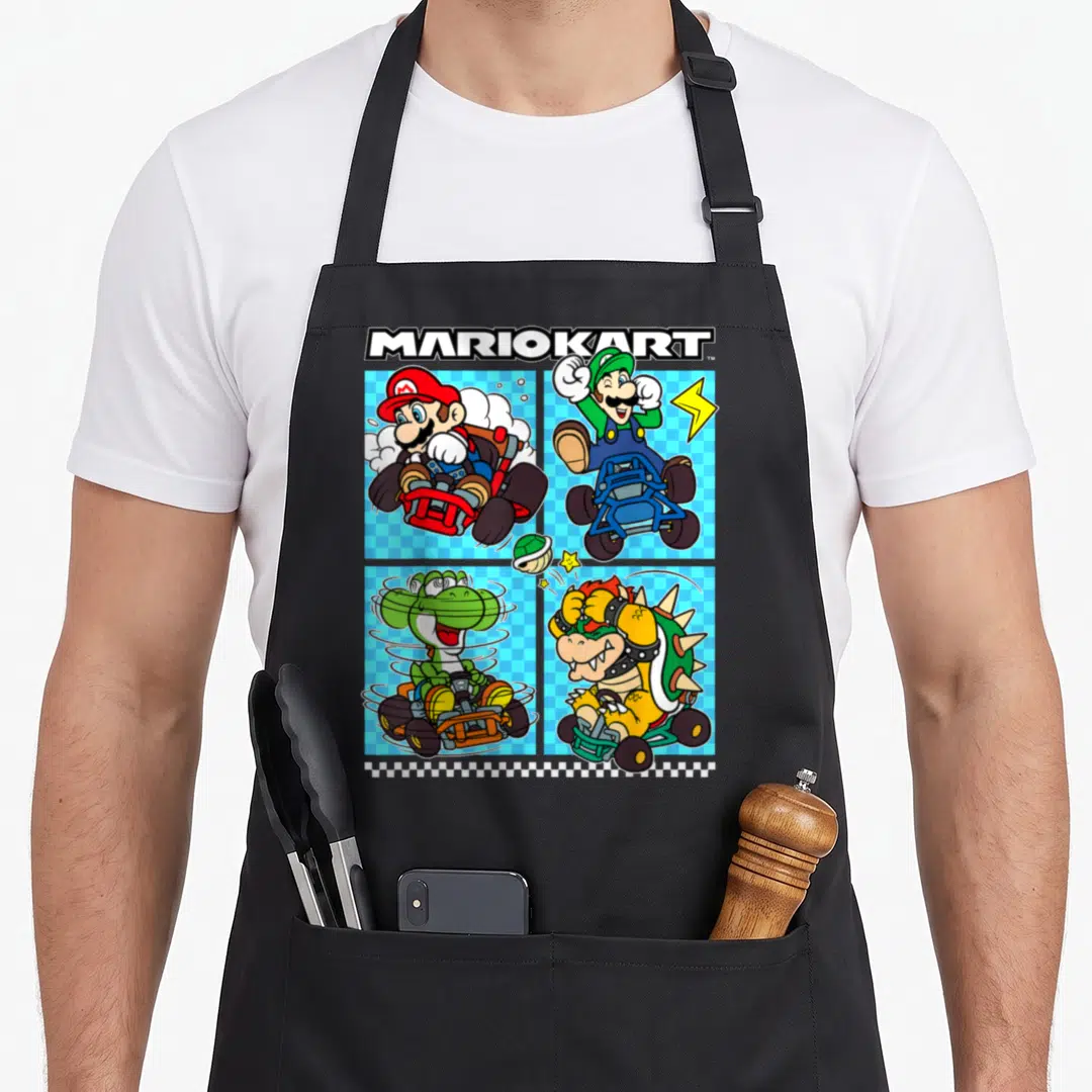 Crew apron for women - MARIOKART text above four racers in go-karts on blue checkered background with green shell — shown on a black cotton canvas apron against a white background