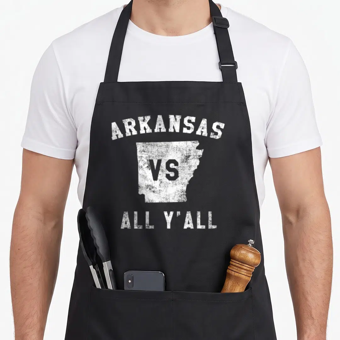 Yall arkansas apron - Distressed white map of Arkansas with arched ARKANSAS VS ALL Y'ALL text — shown on a black cotton canvas apron against a white background
