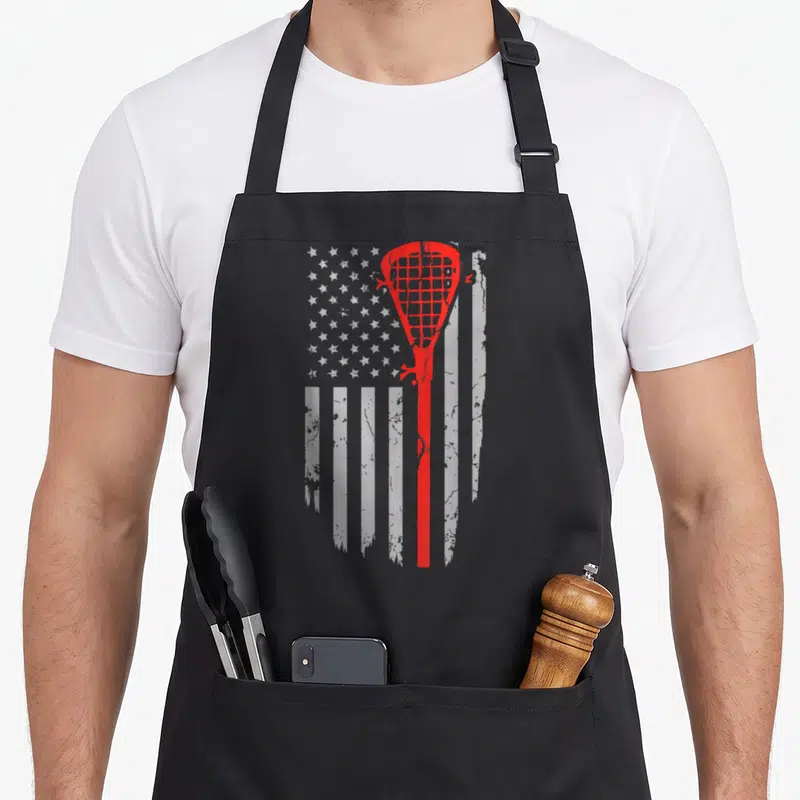 Youth american flag apron - Red lacrosse stick silhouette over distressed white stars and stripes pattern — shown on a black cotton canvas apron against a white background