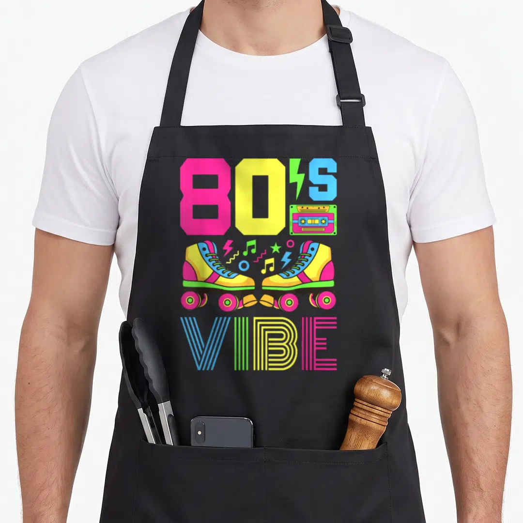 Themed 80s apron - Colorful roller skates cassette tape and 80S VIBE text in pink yellow blue green retro style — shown on a black cotton canvas apron against a white background