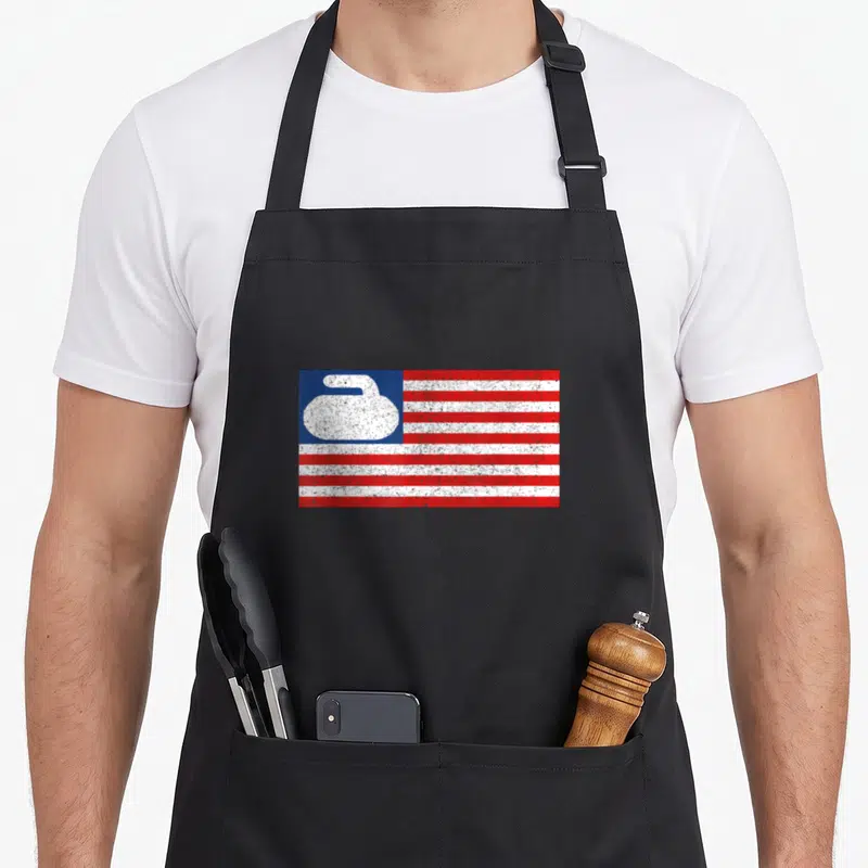 Flag curling stone apron - Distressed red white and blue flag with white curling stone silhouette in blue corner — shown on a black cotton canvas apron against a white background