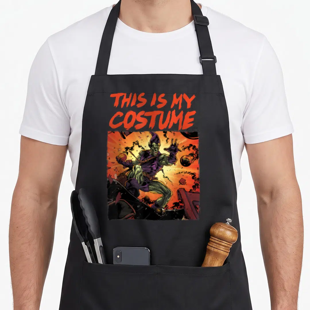 Goblin costume halloween apron - Red text THIS IS MY COSTUME above comic goblin in explosion with orange green purple — shown on a black cotton canvas apron against a white background
