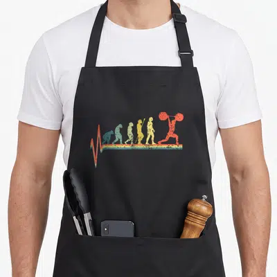 Lifting powerlifting addict apron - Retro evolution sequence ending in red weightlifter with colorful heartbeat line — shown on a black cotton canvas apron against a white background