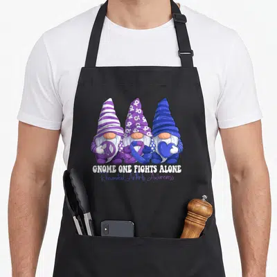 Gnomy rheumatoid ribbon apron - Three gnomes holding peace sign, purple ribbon, and blue heart above awareness text — shown on a black cotton canvas apron against a white background