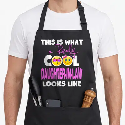 Father mom and daughter aprons - Stacked text saying This Is What A Really Cool Daughter-In-Law Looks Like with two — shown on a black cotton canvas apron against a white background