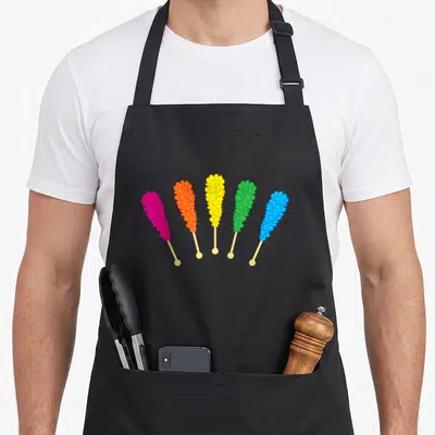Rock candy rainbow apron - Five cartoon rock candy sticks in pink, orange, yellow, green, and blue arranged in a fan — shown on a black cotton canvas apron against a white background