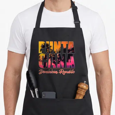 Punta have better apron - PUNTA CANA stacked block letters with sunset palm trees and Dominican Republic script — shown on a black cotton canvas apron against a white background
