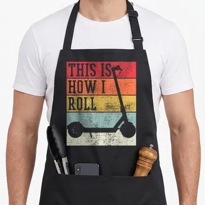 Electro scooter apron - Retro scooter silhouette on red orange yellow blue white stripes with stacked text — shown on a black cotton canvas apron against a white background