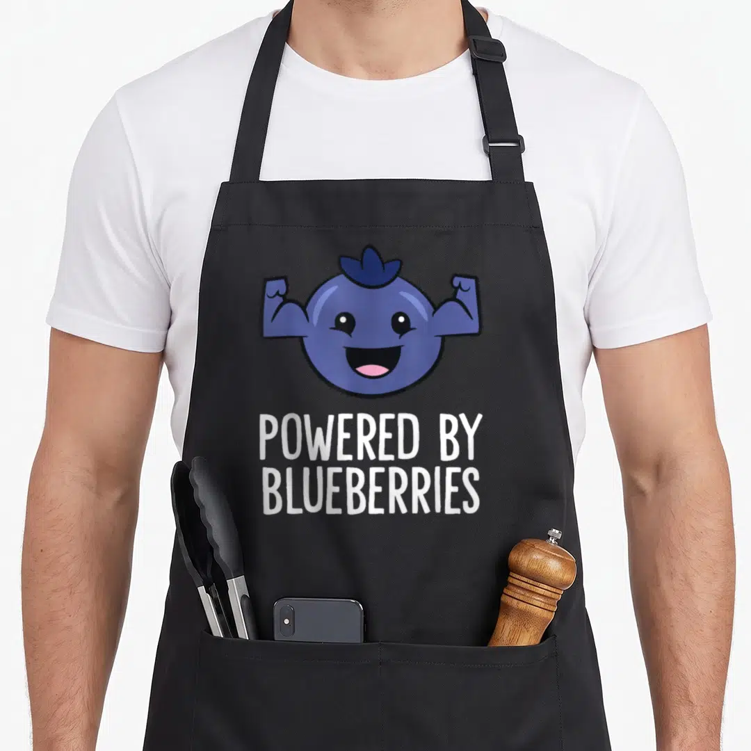 Powered blueberries apron - Cartoon blueberry flexing arms above POWERED BY BLUEBERRIES text in white — shown on a black cotton canvas apron against a white background