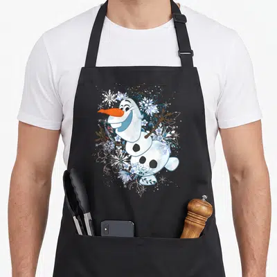 Dancing frozen apron - Snowman with orange nose surrounded by white snowflakes and blue watercolor flowers — shown on a black cotton canvas apron against a white background