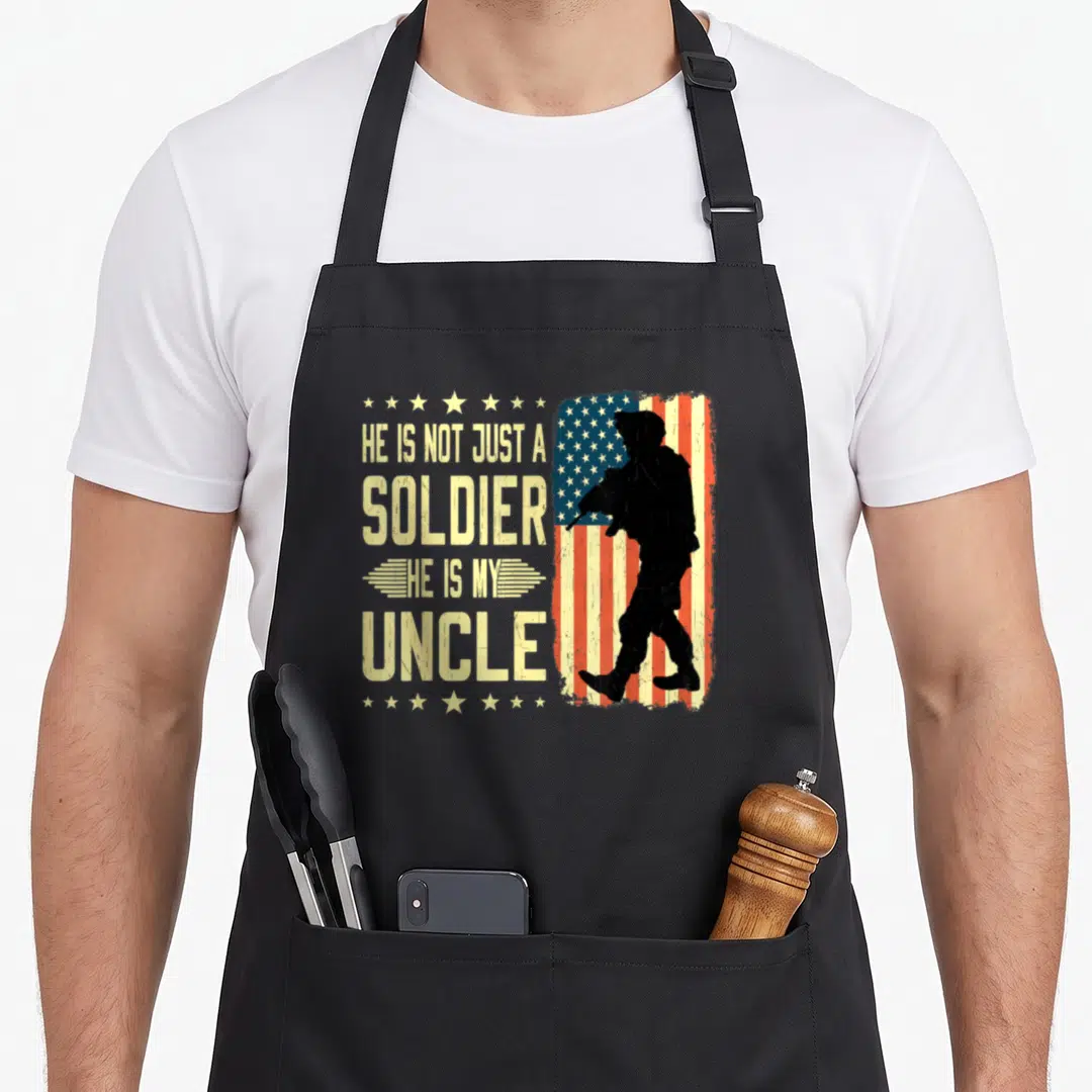 Uncle military apron - Soldier silhouette on distressed flag with He Is Not Just A Soldier He Is My Uncle text — shown on a black cotton canvas apron against a white background