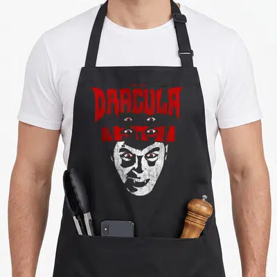 Universal distressed apron - Red Dracula and Myth text with white face and embedded eyes in distressed style — shown on a black cotton canvas apron against a white background
