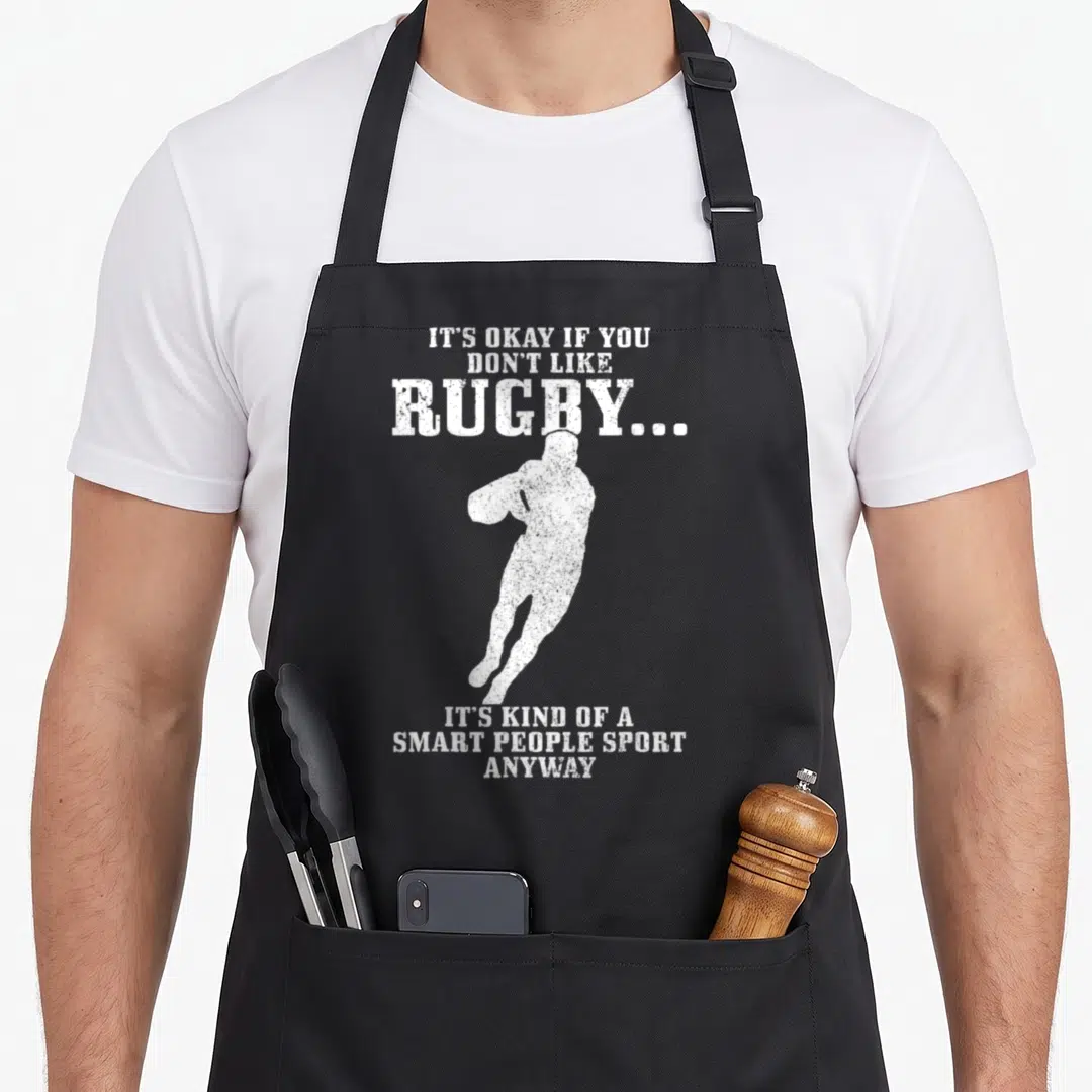 Rugby smart apron - White distressed rugby player silhouette surrounded by sarcastic text about the sport — shown on a black cotton canvas apron against a white background