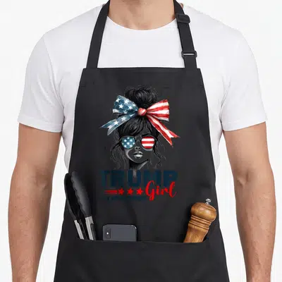 Trump messy aprons - Woman with flag bow and glasses above TRUMP Girl NO APOLOGIES text — shown on a black cotton canvas apron against a white background