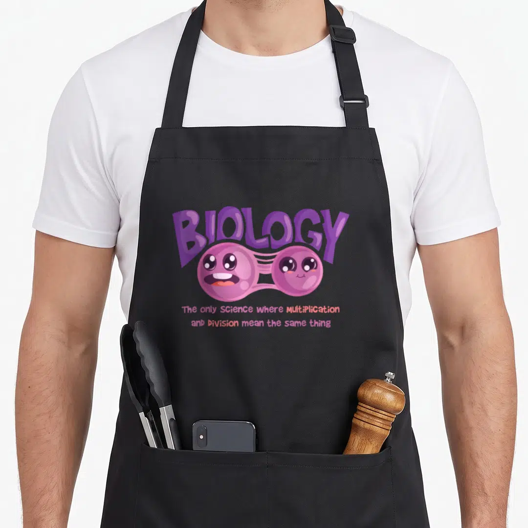 Teaching biology teacher apron - Purple BIOLOGY text above a pink cartoon dividing cell with two lines of text below — shown on a black cotton canvas apron against a white background