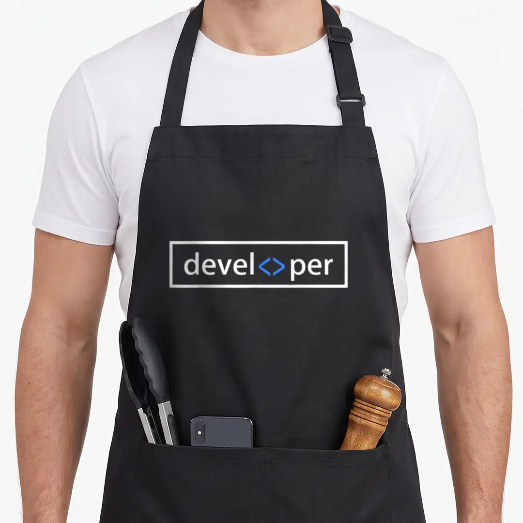 Web programmer apron - White developer text split by blue angle brackets in a white rectangular border — shown on a black cotton canvas apron against a white background