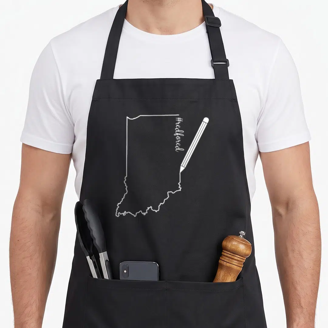 Redfored teacher apron - White Indiana state outline drawn by pencil with vertical #redfored text — shown on a black cotton canvas apron against a white background