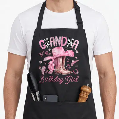 Western rodeo cowgirl aprons - Pink cowboy hat on brown boots with GRANDMA of the Birthday Girl text and western icons — shown on a black cotton canvas apron against a white background