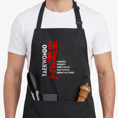 Tenet taekwondo apron - Vertical TAEKWONDO text, red Korean characters, black martial artist silhouette, and five core — shown on a black cotton canvas apron against a white background