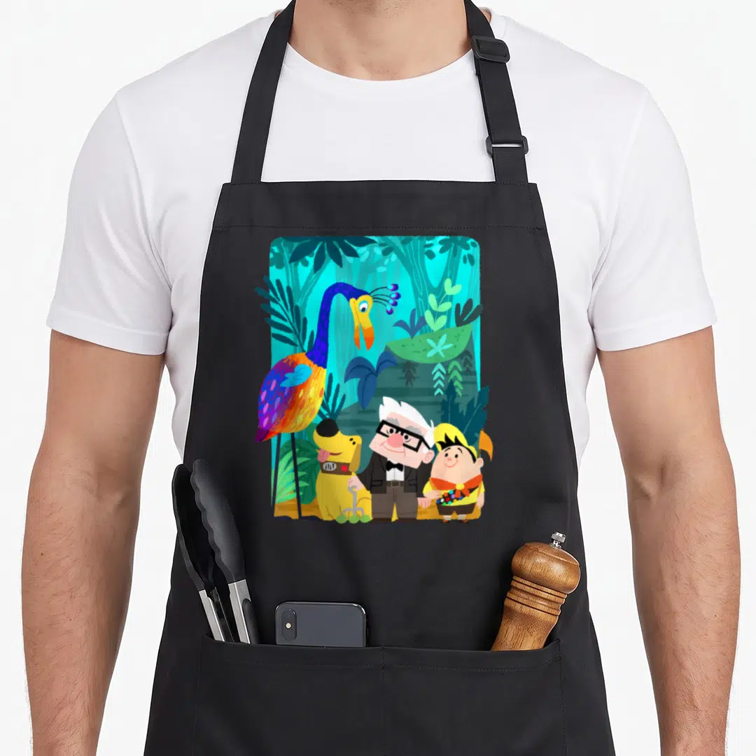 Carl fall apron - Four cartoon characters including a large bird, dog, man, and boy in a colorful jungle setting — shown on a black cotton canvas apron against a white background