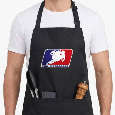 Motocross pro apron - White motocross rider silhouette over blue red background with PRO MOTOCROSS text below — shown on a black cotton canvas apron against a white background
