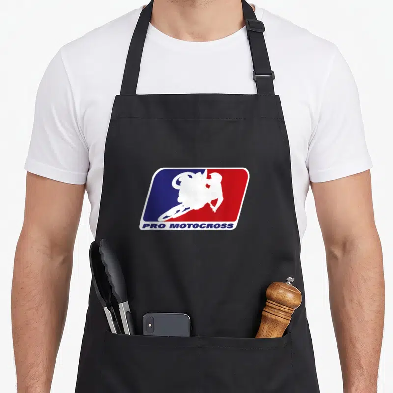 Motocross pro apron - White motocross rider silhouette over blue red background with PRO MOTOCROSS text below — shown on a black cotton canvas apron against a white background