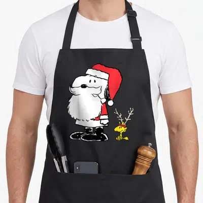 Holiday santa apron - Snoopy Santa and Woodstock reindeer cartoon in white red black and yellow — shown on a black cotton canvas apron against a white background