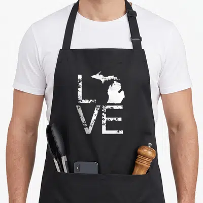 Map pride apron - Distressed white LOVE text with Michigan map replacing the letter O — shown on a black cotton canvas apron against a white background