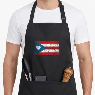 Rico flag pride apron - Distressed red white blue flag with white heart in blue triangle — shown on a black cotton canvas apron against a white background