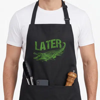 Alligator gatorade apron - Green distressed LATER text above a horizontal alligator lying down — shown on a black cotton canvas apron against a white background