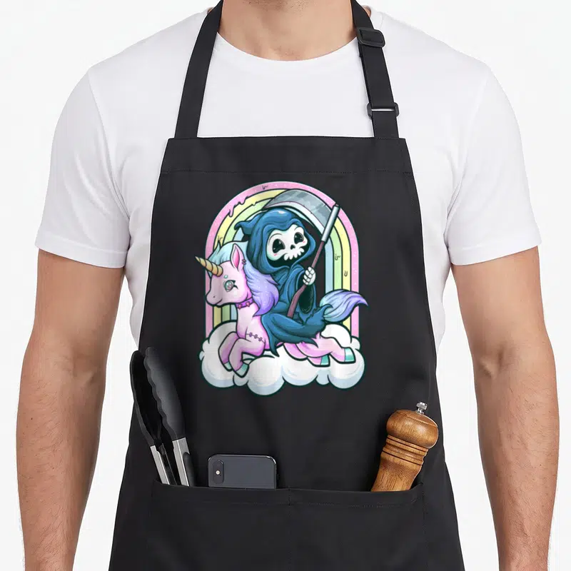 Unicorn goth apron - Cartoon Grim Reaper riding pink unicorn on cloud with rainbow — shown on a black cotton canvas apron against a white background