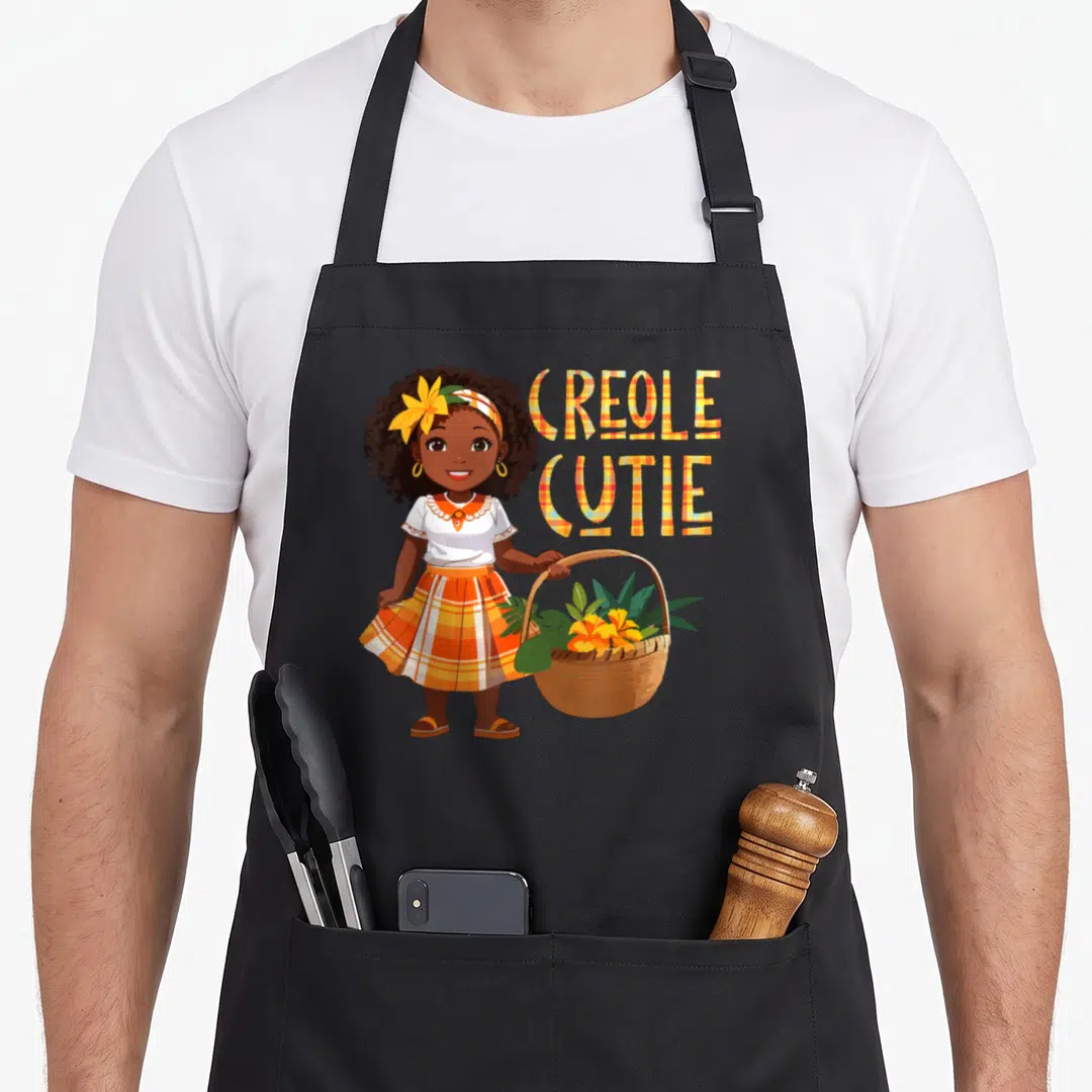 Cutie creole apron - Cartoon girl in plaid skirt holding flower basket next to stacked plaid text CREOLE CUTIE — shown on a black cotton canvas apron against a white background