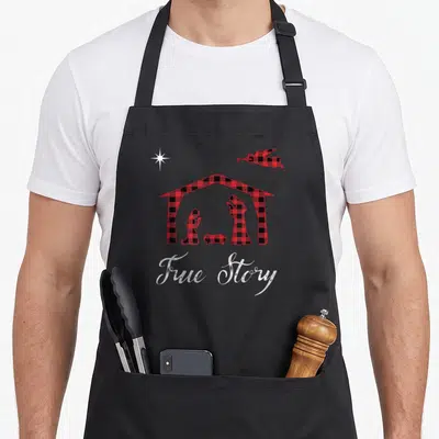 Nativity buffalo plaid christmas apron - Red and black plaid nativity with white True Story text, star and angel — shown on a black cotton canvas apron against a white background