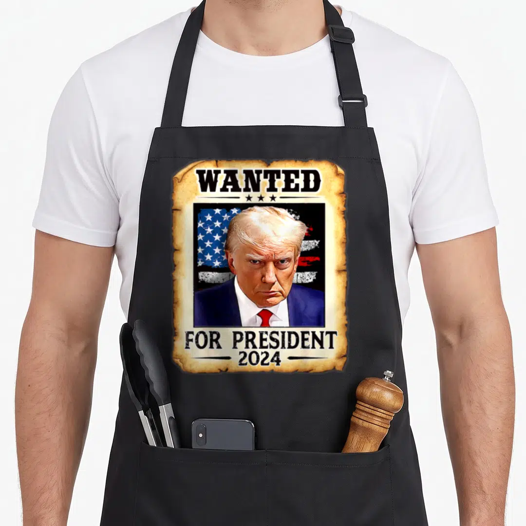 Donald presidents apron - Wanted poster graphic of Donald Trump with American flag and 2024 text — shown on a black cotton canvas apron against a white background