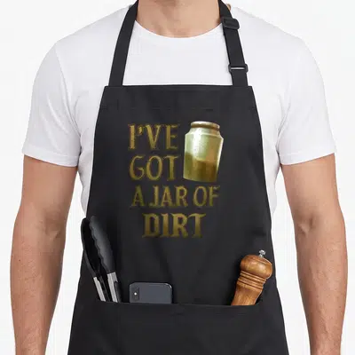Jar sparrows sparrow apron - Stacked gold text reading I've Got A Jar of Dirt beside a brown and silver cartoon jar — shown on a black cotton canvas apron against a white background