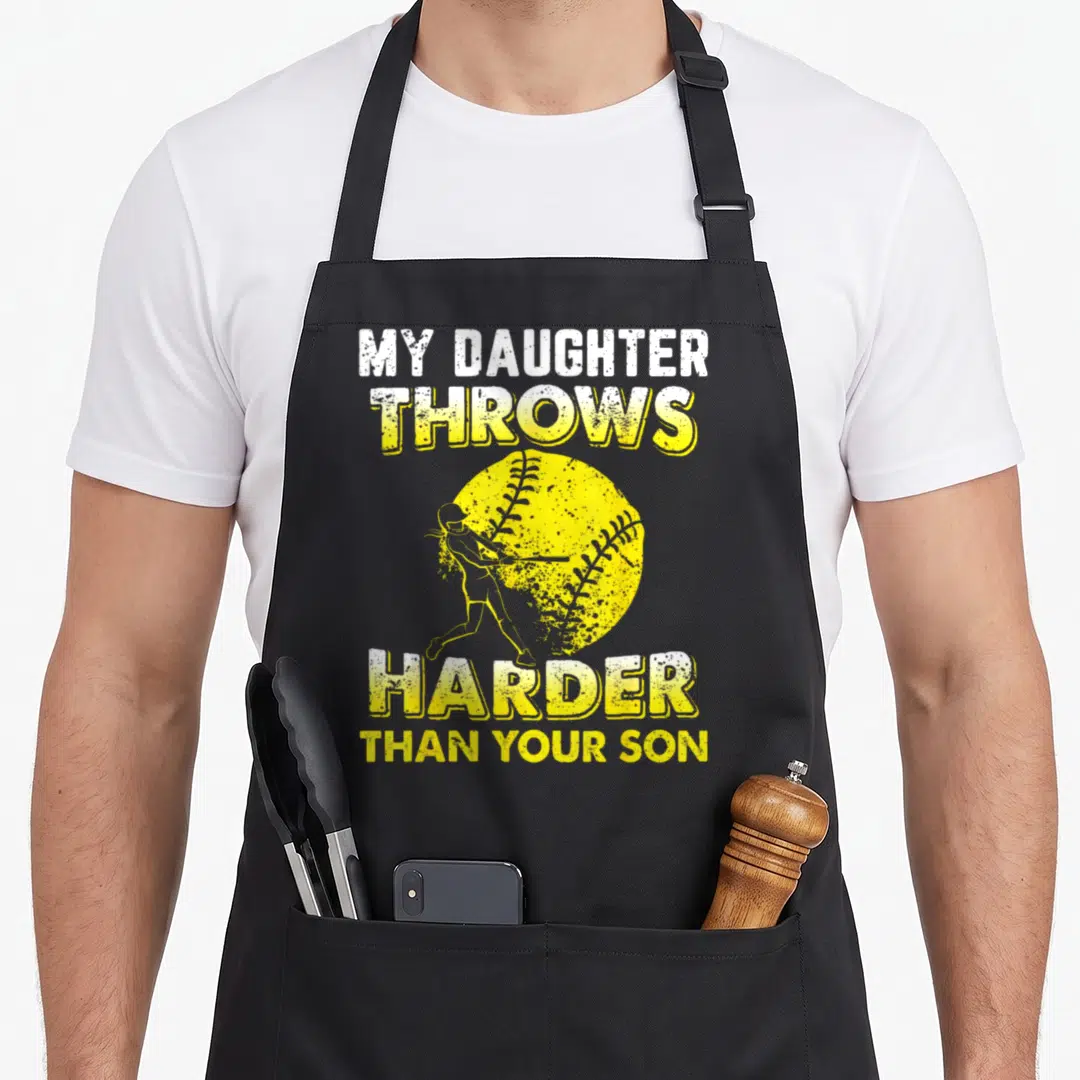 Softball dad and daughter aprons - Yellow softball with girl batter silhouette and text My Daughter Throws Harder Than — shown on a black cotton canvas apron against a white background