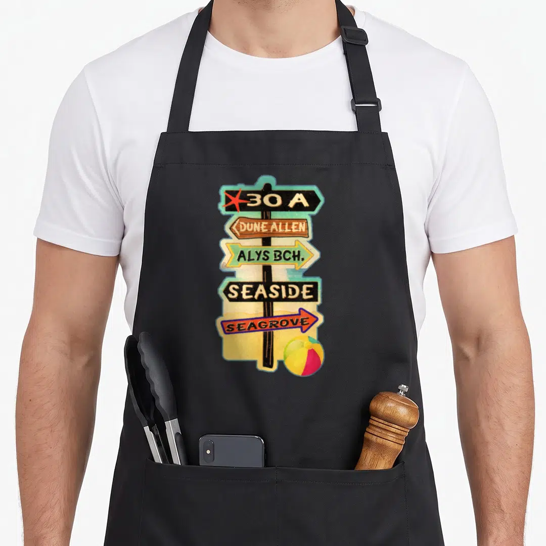 30a florida apron - Cartoon signpost with five directional signs listing coastal towns and a beach ball — shown on a black cotton canvas apron against a white background